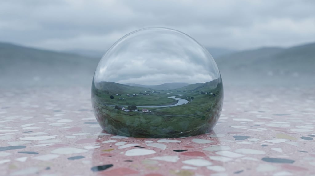 A raindrop at macro scale, the entire surrounding landscape visible refracted and inverted through t