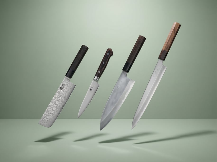 Set of four Japanese kitchen knives floating in a staggered diagonal line — a nakiri with Damascus-p
