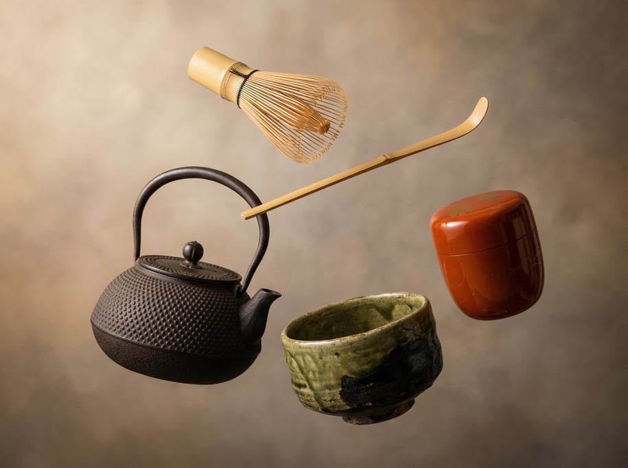 Japanese tea ceremony utensils floating as a curated set — a bamboo whisk with its delicate tines fa
