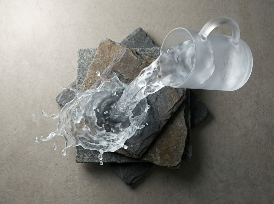 Water simulation frozen mid-pour over stacked stone plates (haf2rhrg)