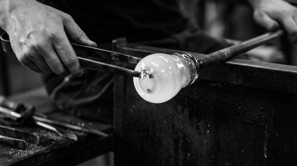 Molten glass being shaped by a glassblower, glowing amber against a dark workshop