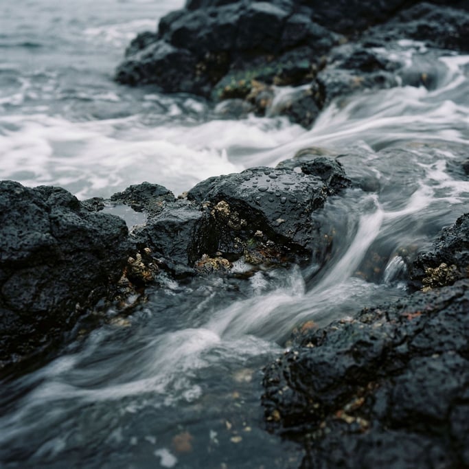 Ocean waves over black volcanic rock, long exposure turning water to silk