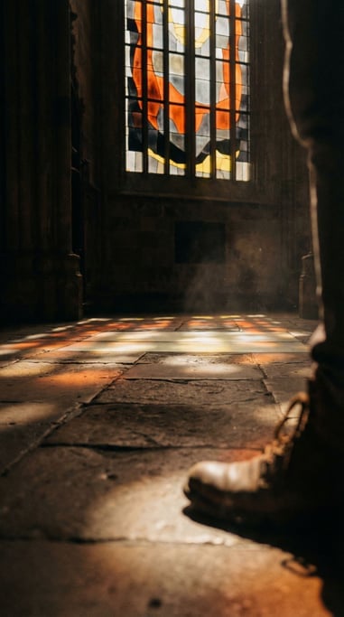 Sunlight through cathedral stained glass, colored light patterns on a stone floor (d)