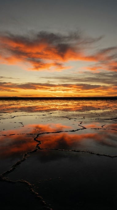 A salt flat at sunset, perfectly reflective surface mirroring clouds