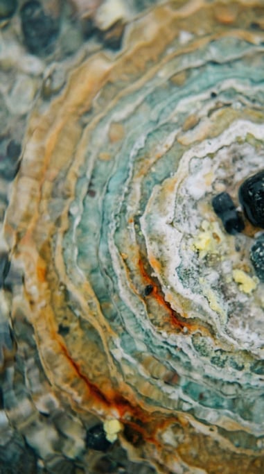 Volcanic hot spring, concentric rings of mineral deposits in orange, turquoise, and white