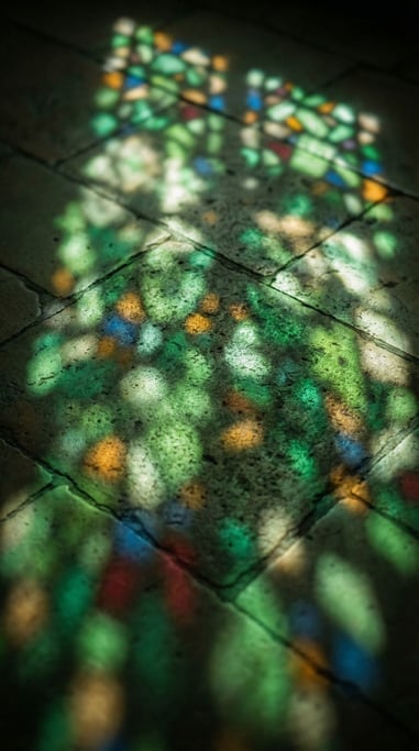 Sunlight through cathedral stained glass, colored light patterns on a stone floor