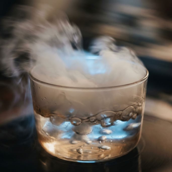 Dry ice sublimating in warm water, roiling fog and bubbles, backlit from below in cool blue