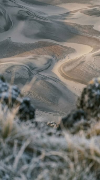 Sand dunes seen from above, abstract curves and soft shadows in cool morning light (r)
