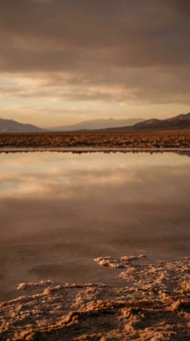 A salt flat at sunset, perfectly reflective surface mirroring clouds (c6pbp5qv)