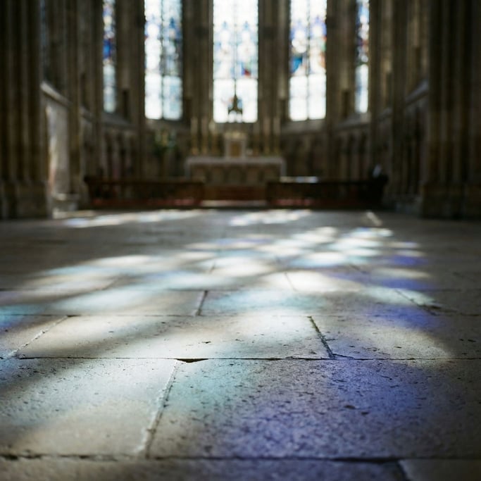 Sunlight through cathedral stained glass, colored light patterns on a stone floor (lo)