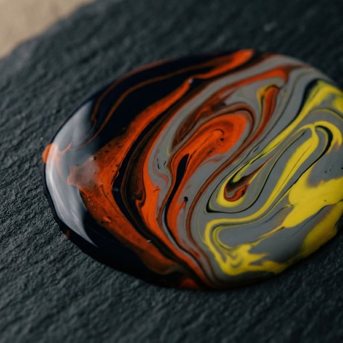 A puddle of spilled nail polish in multiple colors, swirled but not mixed, still wet (9in6gy8c)