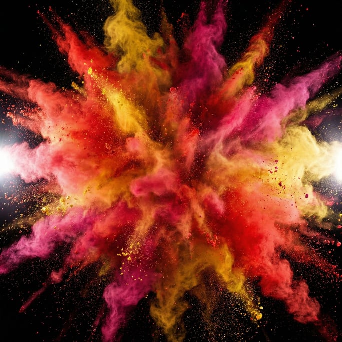 Colored powder detonates against pure black — a chaotic cloud of vermillion red and saffron yellow and magenta pink particles frozen mid-air