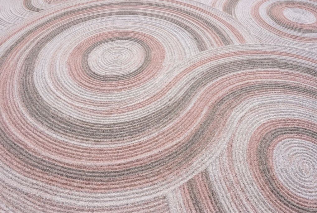 A smooth flowing landscape of colored sand in pale rose and warm grey and white