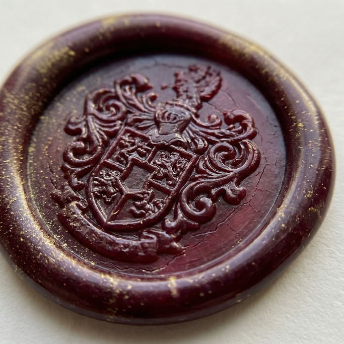 Deep burgundy sealing wax fills the frame at magnified scale — the impression of an ornate stamp showing its carved pattern in relief with crisp edges and soft rounded impressions