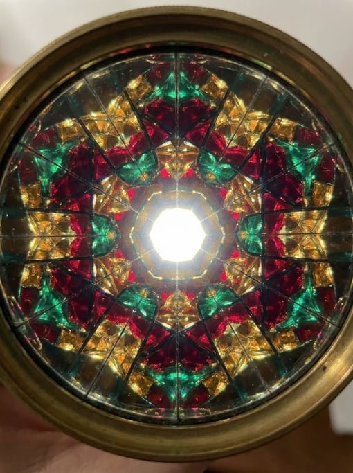 Rich jewel tones of ruby and emerald and gold explode in six-fold symmetry — kaleidoscope mandala-li