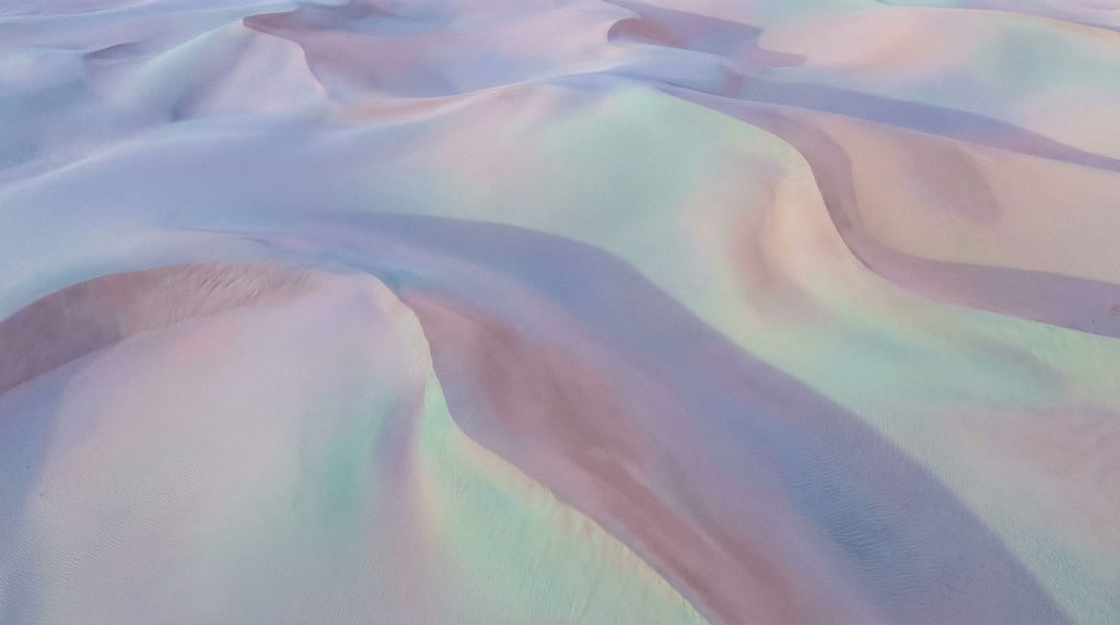 Sand dunes seen from above, abstract curves and soft shadows in cool morning light