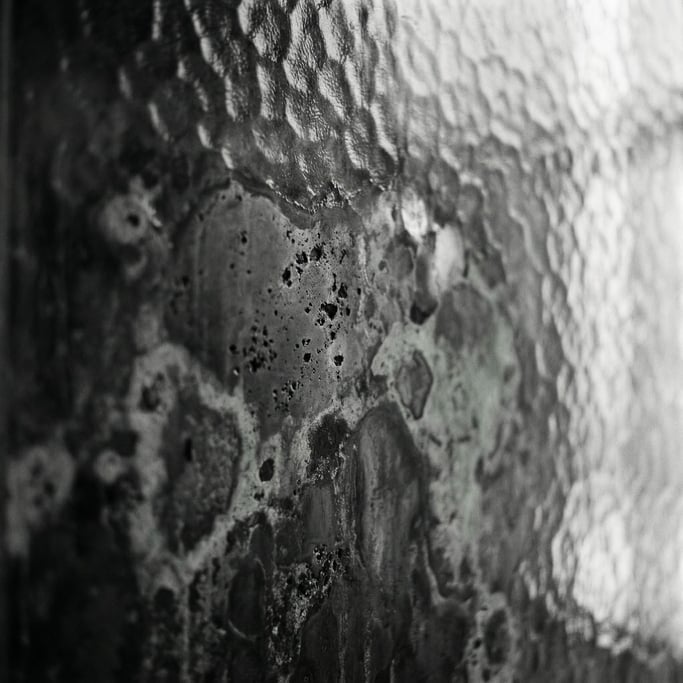 A close-up of oxidized copper surface, verdigris green against dark metallic gray (rvebgbit)