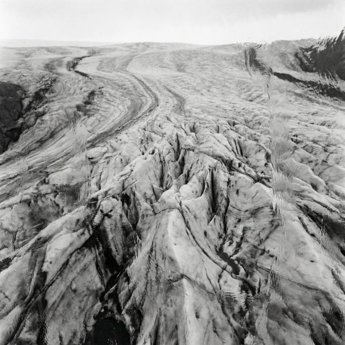 Aerial view of a glacier, crevasses and blue-white ice fields, abstract patterns from above (6sf7rcc8)