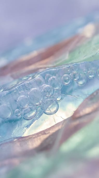 Frozen air bubbles trapped in clear blue ice, macro shot, cool crystalline tones