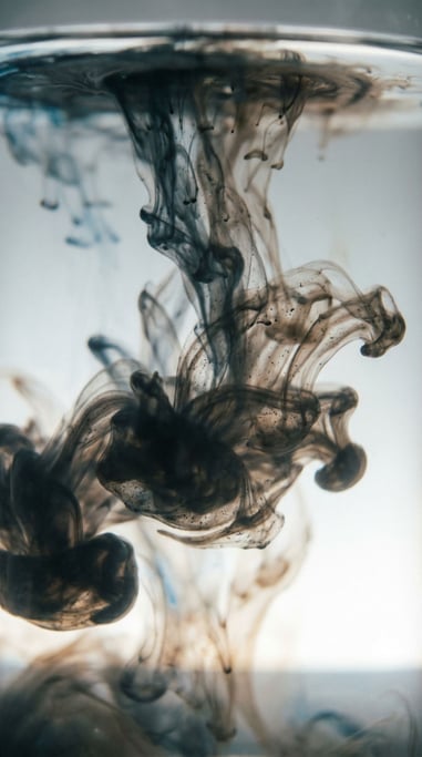 Ink dropped into water, tendrils expanding in slow motion, backlit from below