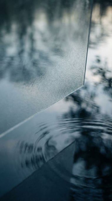 Ripples in a still pond distorting reflected sky and trees into abstract color fields (twseyks)