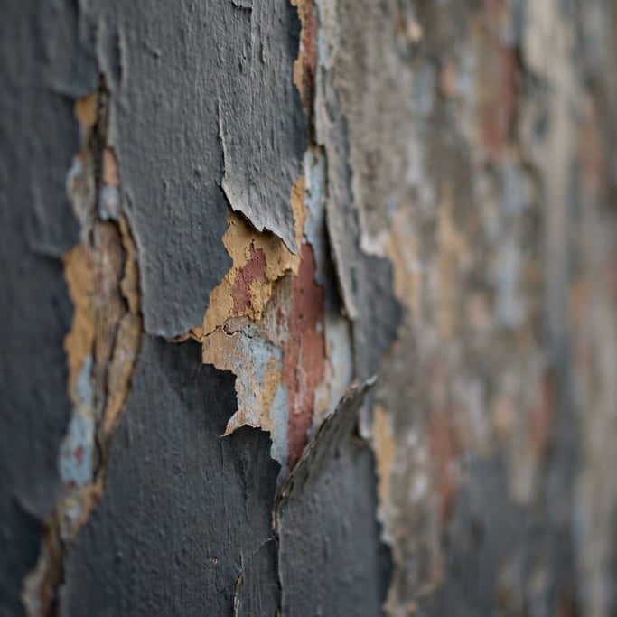 Peeling paint on a weathered wall revealing layers of color underneath, texture and decay (fbs7xi6s)