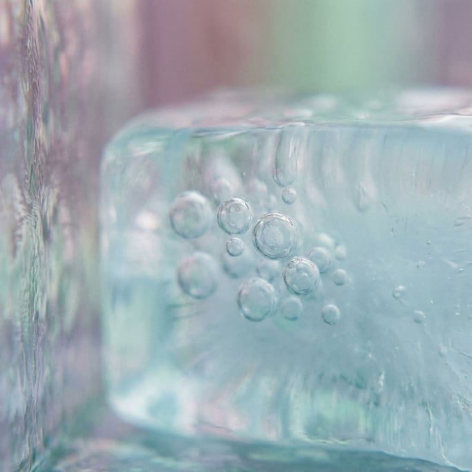 Frozen air bubbles trapped in clear blue ice, macro shot, cool crystalline tones (pmug1lt9)