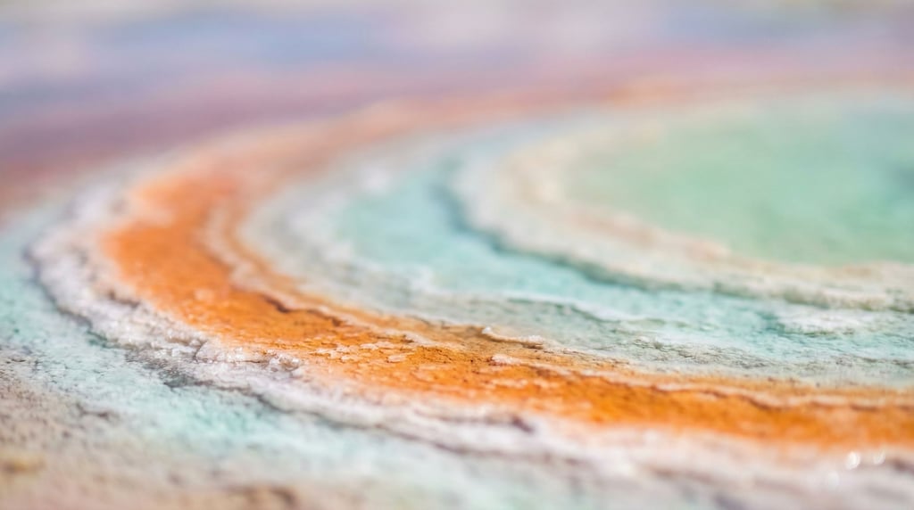 Volcanic hot spring, concentric rings of mineral deposits in orange, turquoise, and white (fn5fykn3)