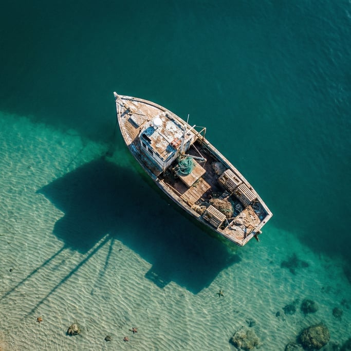 Overhead shot of a small wooden fishing boat in deep teal water