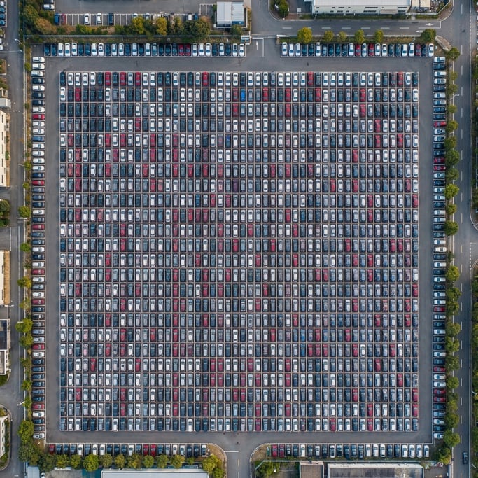 Overhead shot of a parking lot from above with cars arranged in a precise geometric grid