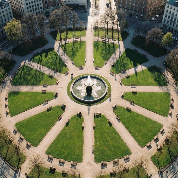 Overhead shot of a city park with a circular fountain at center