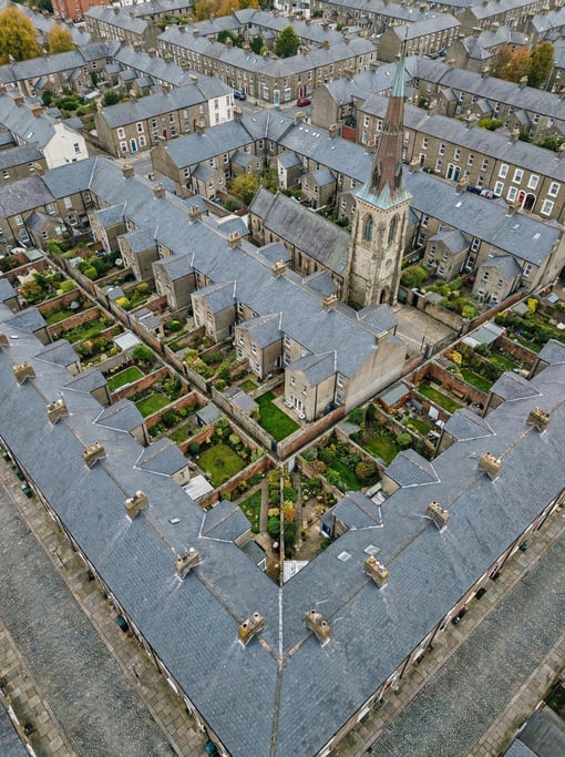 Top-down view of a dense residential neighborhood with identical row house rooftops in dark grey sla