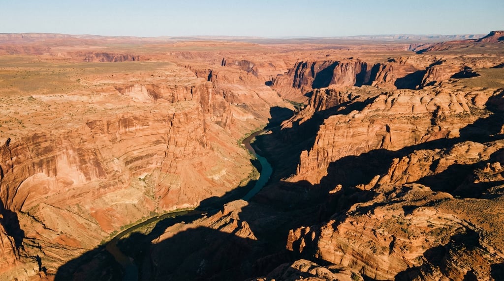 Wide drone view of a desert canyon from above, showing layered red and orange sandstone walls