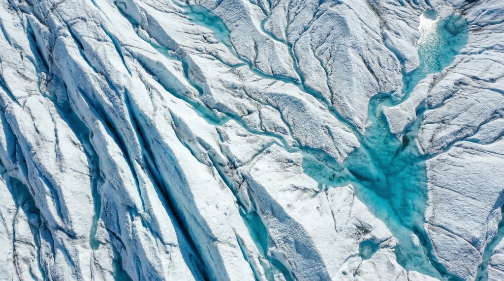 Top-down drone shot of a glacier surface with deep blue crevasses, white snow ridges