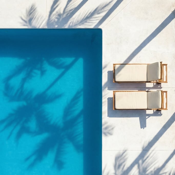 Overhead view of a cerulean blue swimming pool surrounded by white concrete deck
