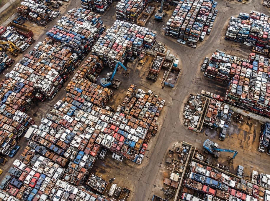 Aerial view of a scrapyard from above with crushed cars stacked in colorful blocks