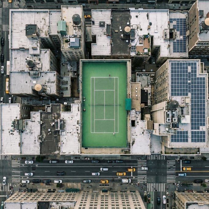 Overhead drone shot of a rooftop tennis court in a dense city