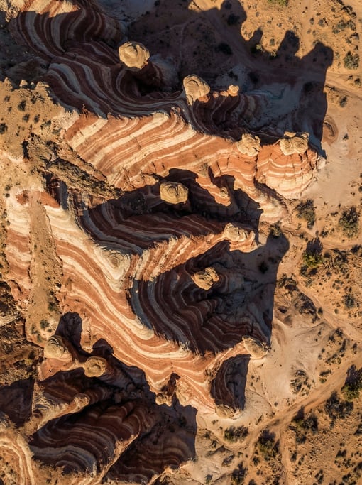 Top-down view of a desert rock formation with distinct horizontal strata layers in red, cream