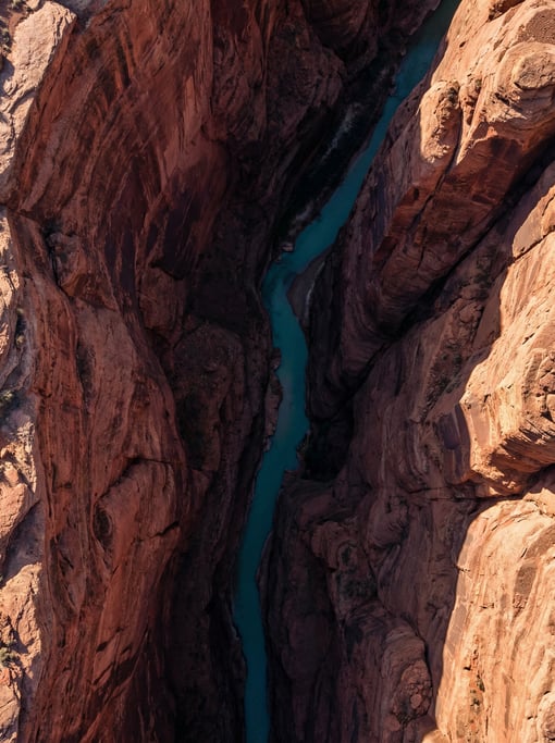 Top-down view of a narrow slot canyon with a river at the bottom