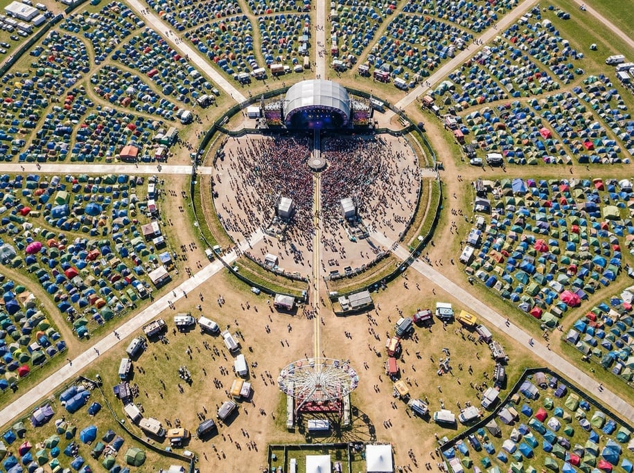 Drone view of a music festival site from above with a circular main stage, radiating walkways