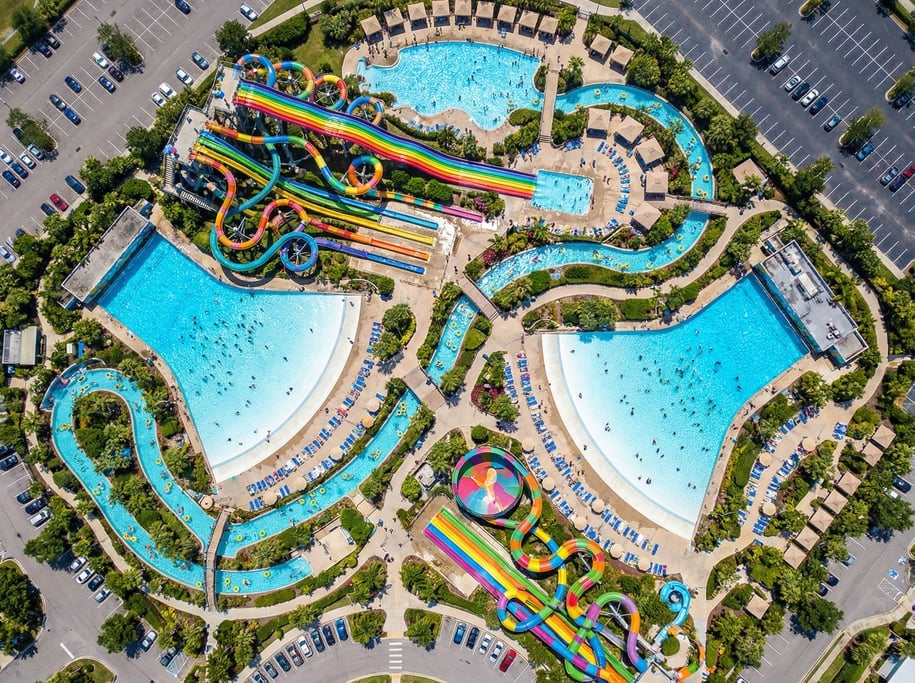 Drone view of a water park from above with colorful slides as winding ribbons