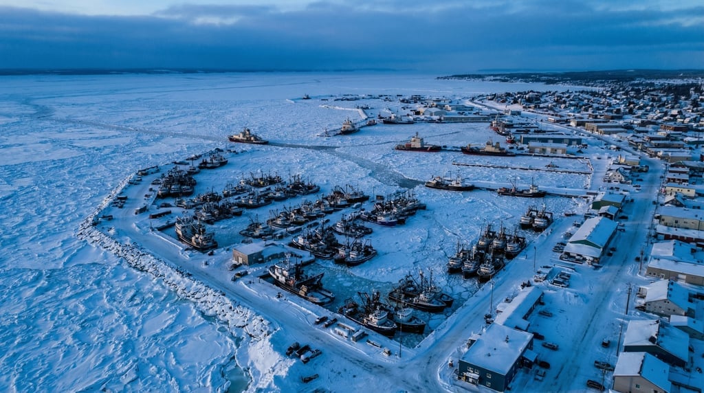 Wide aerial of a frozen harbor with boats trapped in pack ice