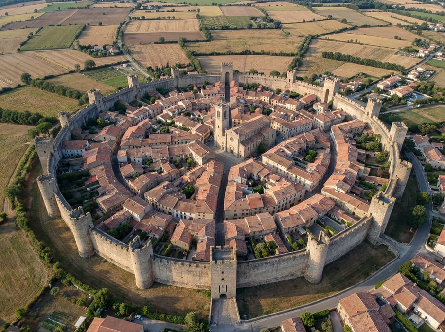 Drone view of a medieval walled town from above showing the intact fortification walls forming a com