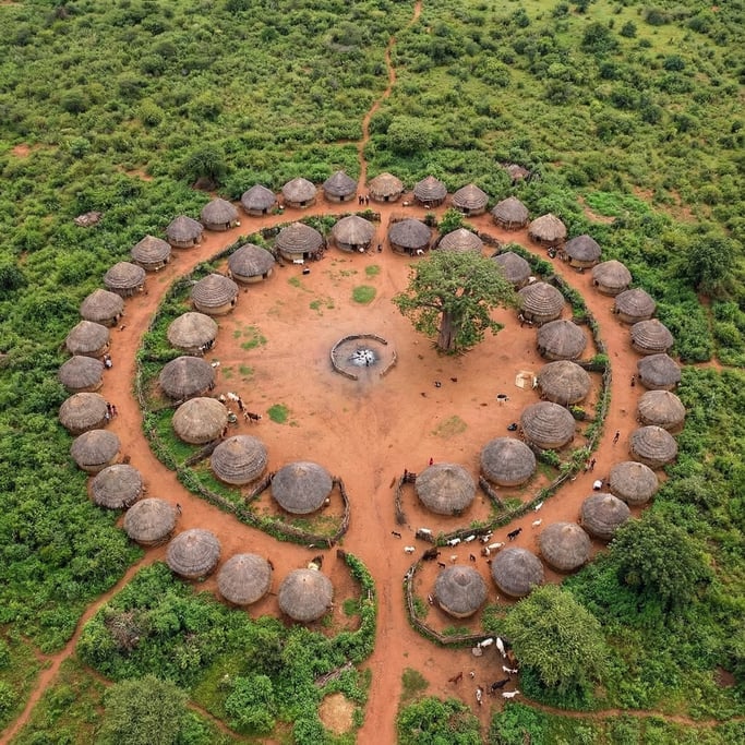 Overhead shot of a traditional circular African village with thatched-roof huts arranged in a ring a