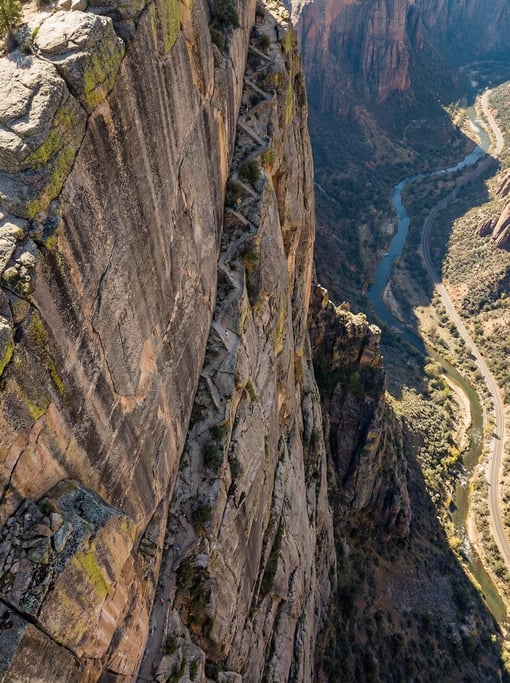 Top-down aerial of a vertical cliff face with a narrow goat trail zigzagging up the rock