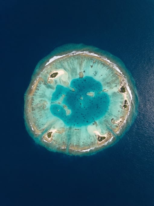 Drone view of a coral atoll from high altitude showing the complete ring structure