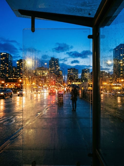 View through a bus shelter glass panel overlooking a cosmopolitan cityscape at blue hour