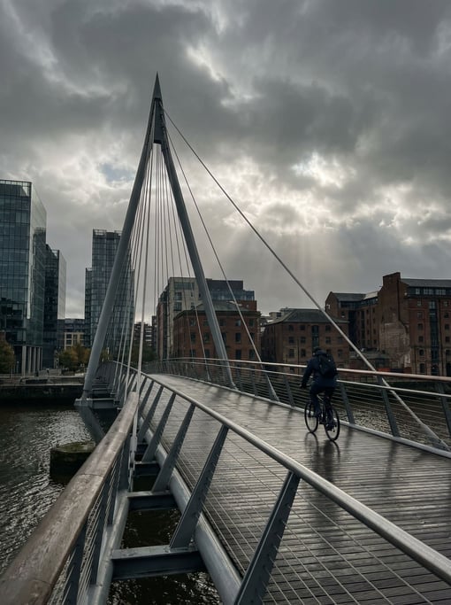 Modern cable-stayed pedestrian bridge under dramatic clouds