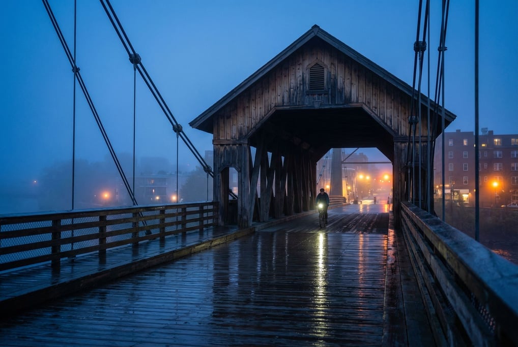 Covered wooden footbridge at dusk, cables disappearing into mist