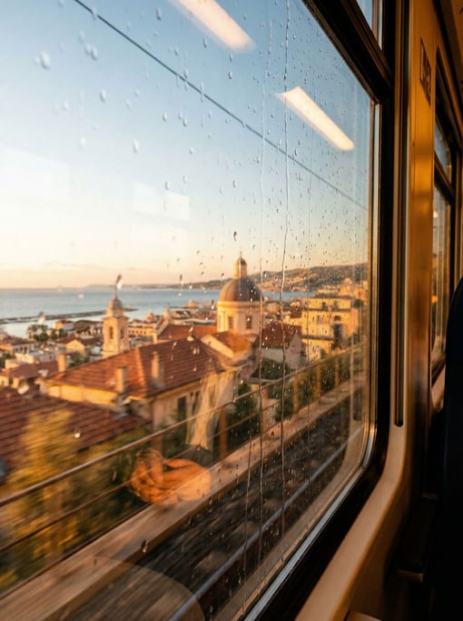View through a train window speeding past the city overlooking a Mediterranean cityscape at golden h